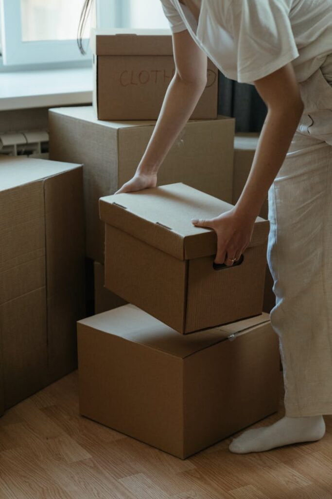 Person in White Pants Holding Brown Cardboard Box